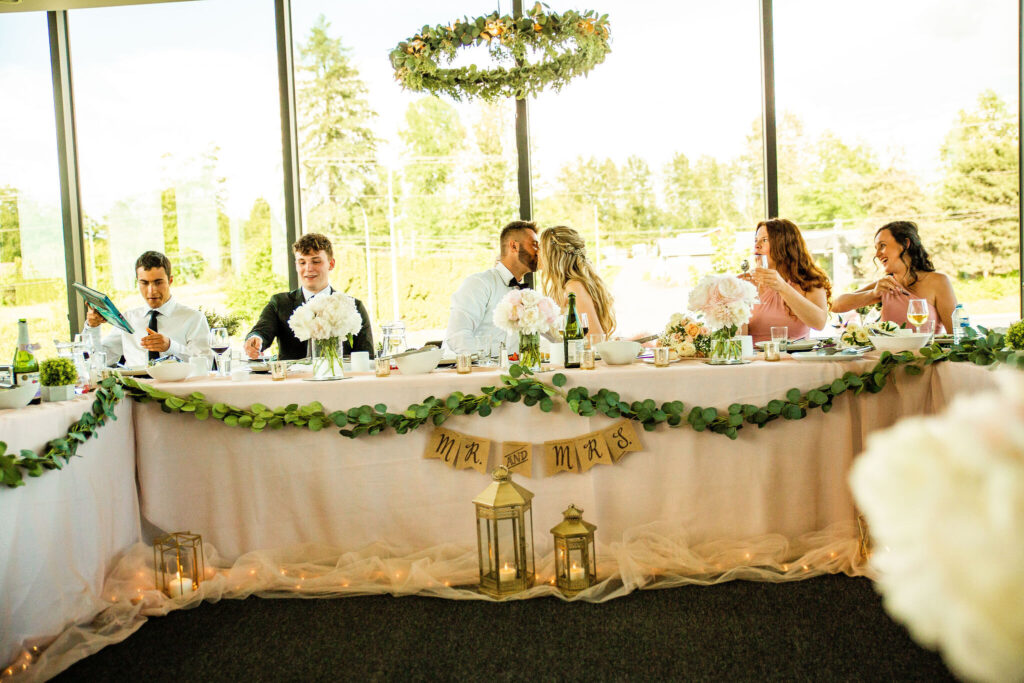 Kissing at the dinner table at a Redwoods Golf Course Wedding