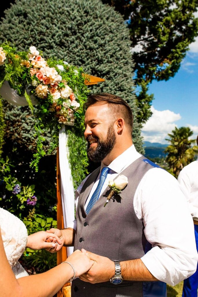 Groom holding bride's hands during their backyard wedding ceremony in BC