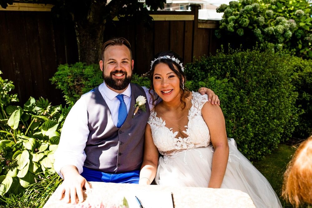 Bride and groom smiling at their backyard wedding ceremony in BC