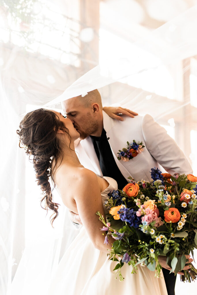 Newlyweds kissing with bouquet of flowers