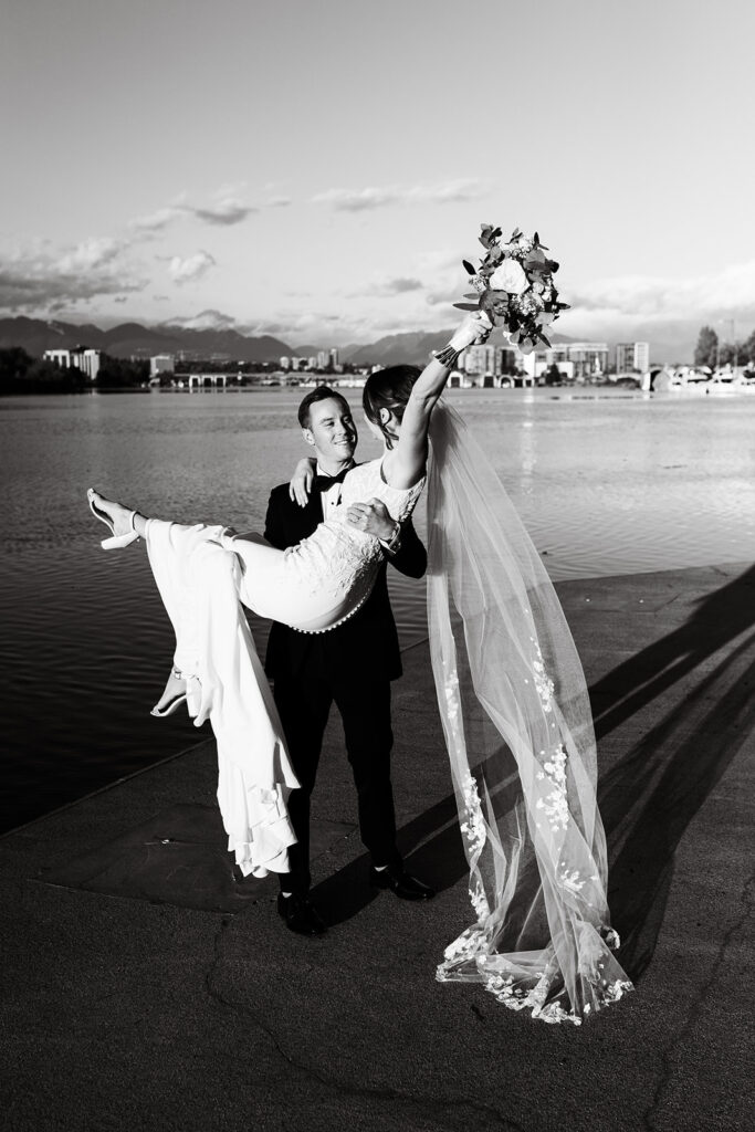 Black and white wedding photo of groom holding bride