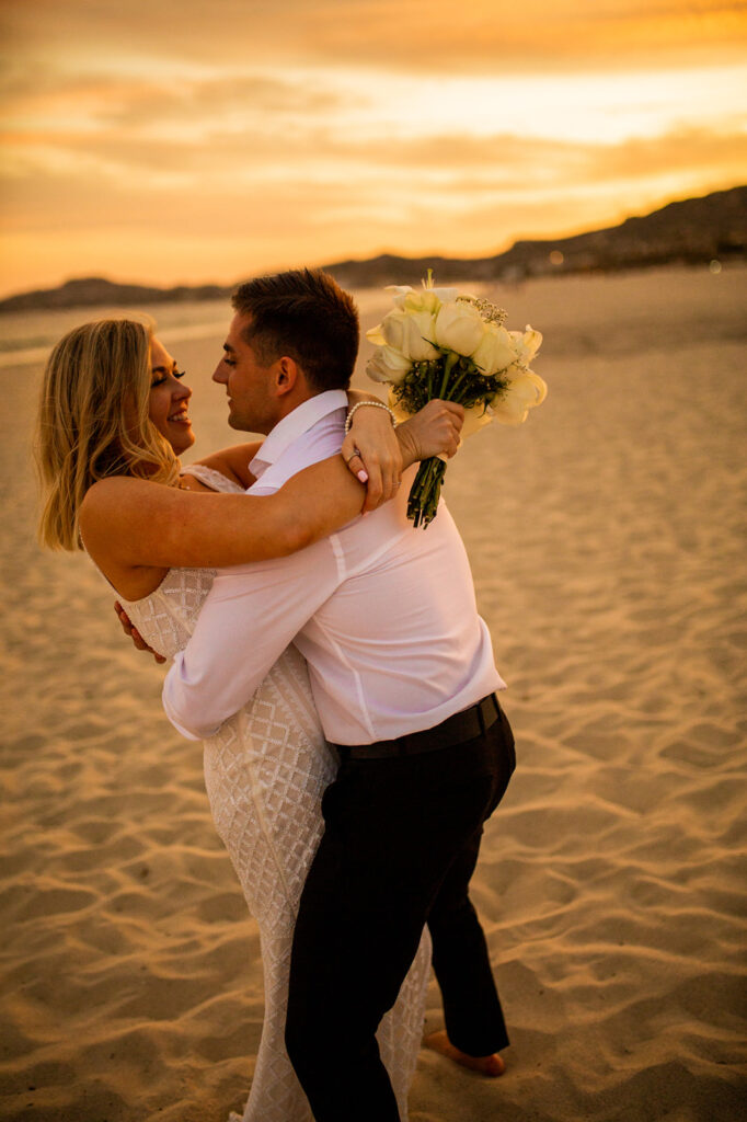 Newlyweds kissing at sunset on the beach in Cabo San Lucas