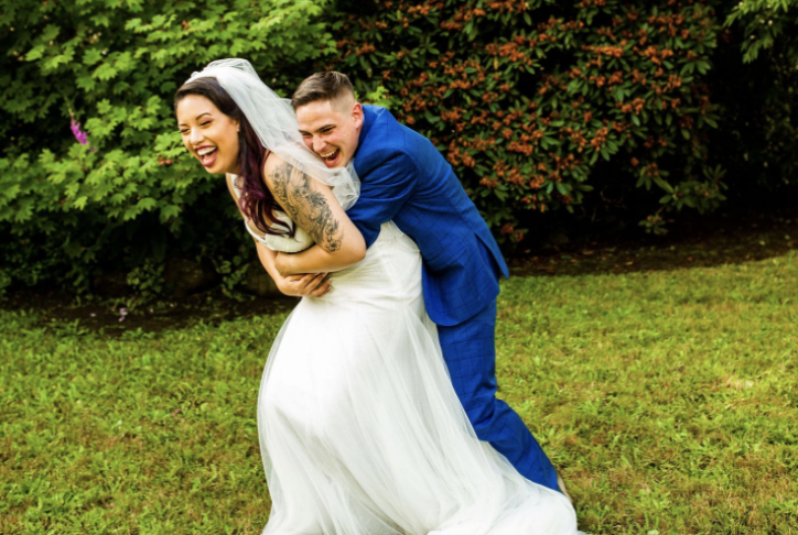Fun wedding photos of a groom hugging a bride while laughing