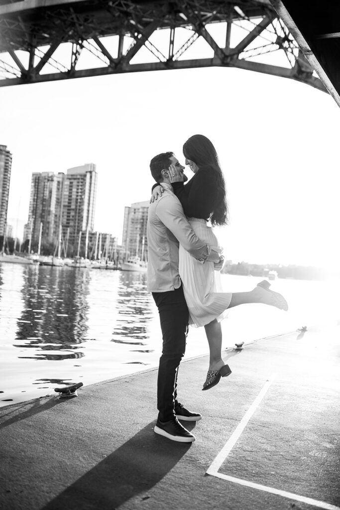 Black and white photo of couple kissing during their engagement shoot in Vancouver on the water