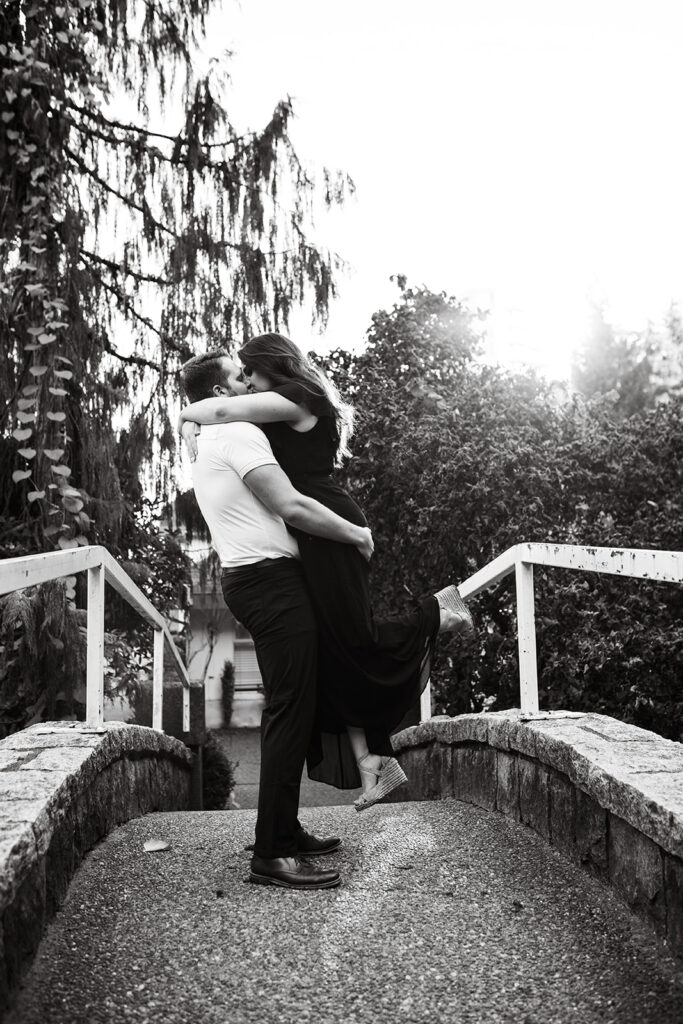 Black and white portrait of couple kissing on a bridge during their engagement shoot in Vancouver