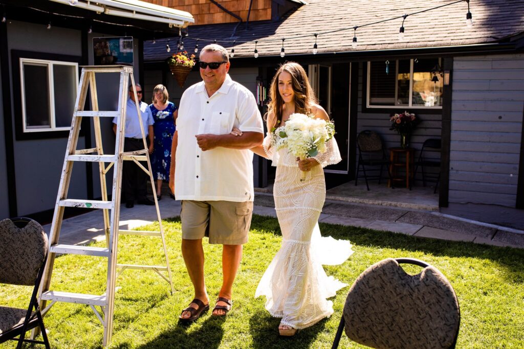 Dad walking bride in her backyard wedding reception