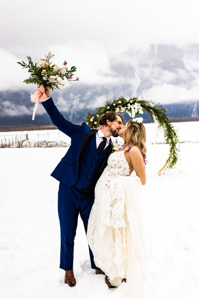 Newlyweds kissing in a snowy backdrop