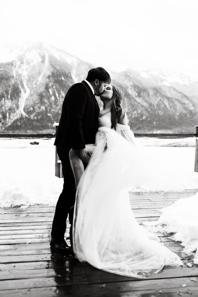 Black and white photo of couple kissing with icy mountain backdrop