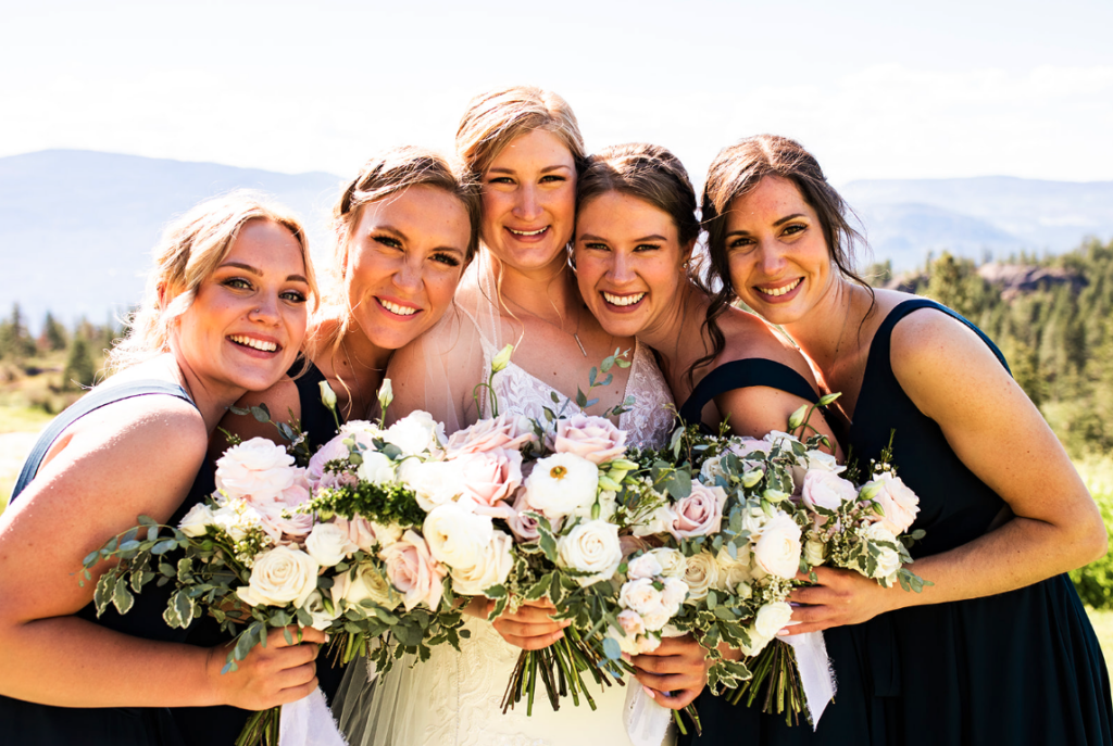 Bride and bridesmaids smiling at a sunny Okanagan wedding